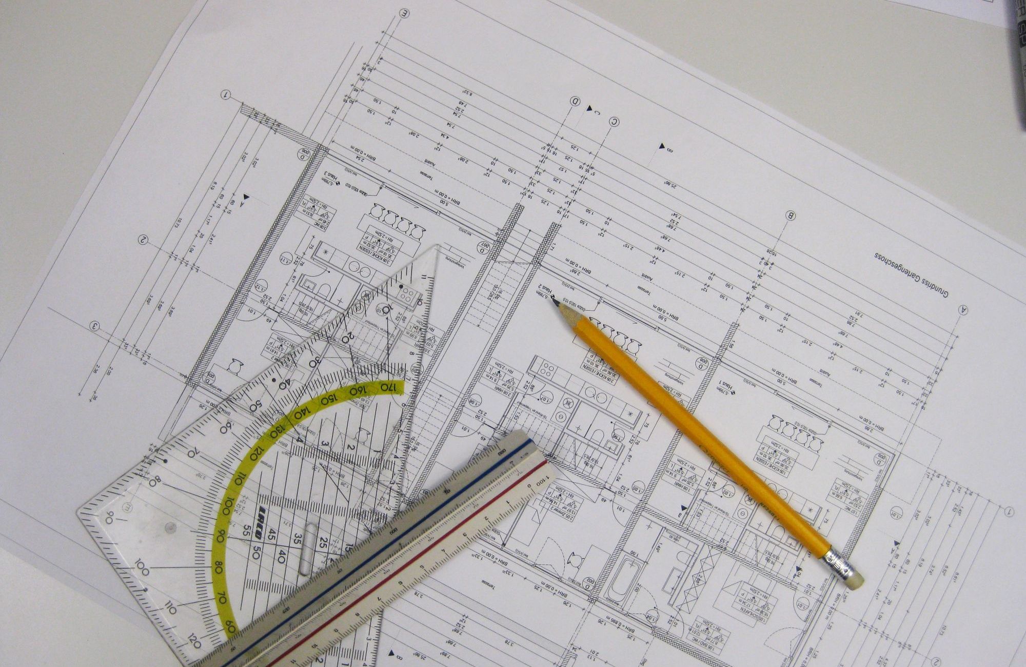Architektenschreibtisch mit einem Grundriss, Dreieck, Maßstab und Bleistift